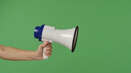A woman hand holding a megaphone on a green chroma key background. Shot for designs related to office, business, education, training, or social matters.
