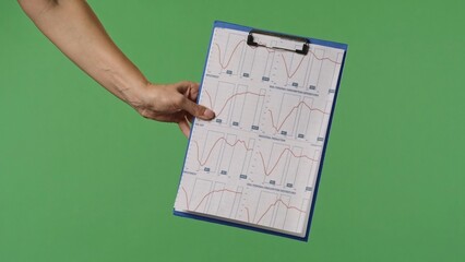 A woman hand holding a clipboard with an economic graphs on a green chroma key background. Shot for...
