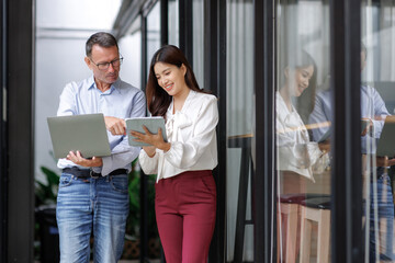 Business professionals collaborating, discussing data on laptop and tablet