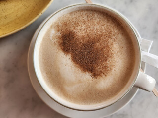 Overhead flat lay shot of a cappuccino with cinnamon and a pastry on the side.