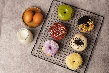 Colorful donuts with milk and eggs on a cooling rack, symbolizing sweet temptation that a child is not allowed to eat.