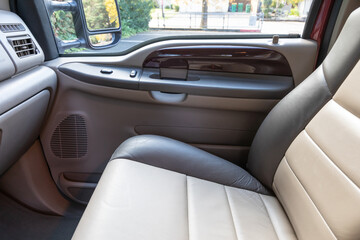 Rear two row beige leather bench seats, interior of an older 2004 American 4x4 family suv truck.   Shown in natural daylight, highlighting clean and well-preserved cabin details, speakers, armrests 