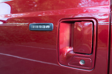 Fototapeta premium Close-up of keypad door lock on a red 2004 American 4x4 family SUV showing numeric entry buttons and handle on metallic paint surface, illustrating classic exterior vehicle design detail