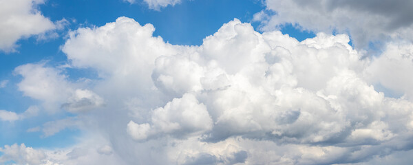 Panoramic view of blue sky with large fluffy cumulonimbus clouds piling up on the horizon line on a...
