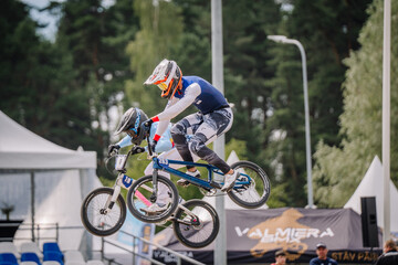 Fototapeta premium Valmiera, Latvia - July 12, 2025: BMX rider performing a jump at a cycling event with spectators in background. BMX European championships