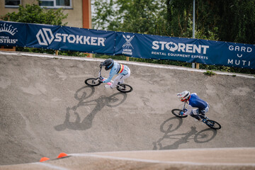Fototapeta premium Valmiera, Latvia - July 12, 2025: BMX racers competing on track with Stokker and Storen banners in background. BMX European championships