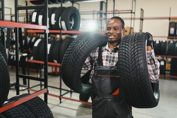 Portrait of African american warehouse worker standing by the pile of new car tires