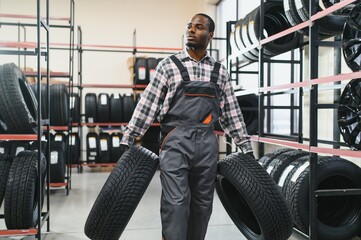 Professional African american worker with tire. Man is in the tire fitting car service