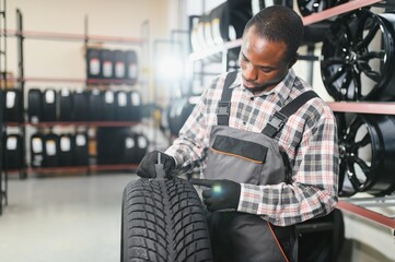 A professional African american worker in a car service measures the tread diameter of a wheel with...