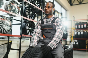 Portrait of African american warehouse worker standing by the pile of new car tires