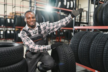 Professional African american worker with tire. Man is in the tire fitting car service