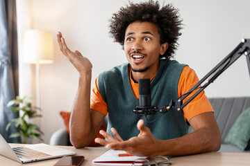 Stressed amazed African American man podcaster using microphone talking sitting in home studio