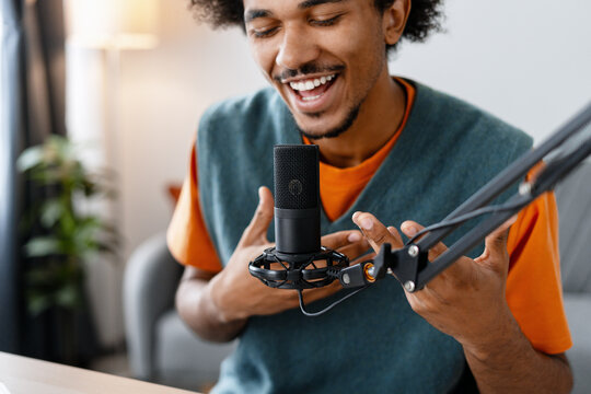 African American man podcaster talking, recording podcast, using microphone selective focus, closeup