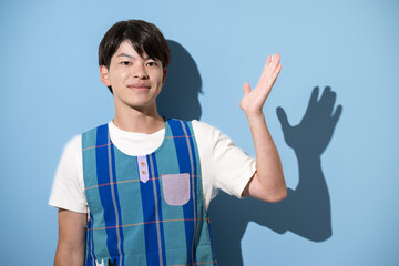 エプロンを着てオススメや紹介のポーズをする男性　保育士・介護士などのイメージ　水色背景のカメラ目線	