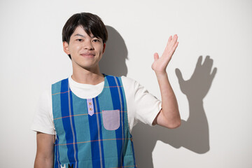 A man wearing an apron striking a pose to recommend or introduce something Evoking the image of a childcare worker or caregiver White background, looking directly at the camera