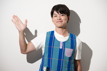 エプロンを着てオススメや紹介のポーズをする男性　保育士・介護士などのイメージ　白背景カメラ目線