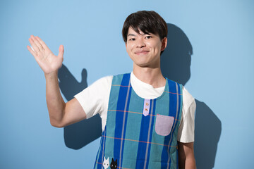 エプロンを着てオススメや紹介のポーズをする男性　保育士・介護士などのイメージ　水色背景のカメラ目線	