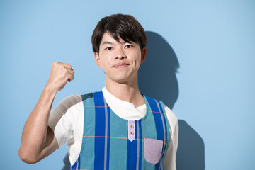 エプロンを着てガッツポーズをする男性　保育士・介護士などのイメージ　水色背景