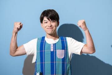 エプロンを着てガッツポーズをする男性　保育士・介護士などのイメージ　水色背景
