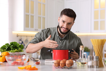 Smiling man cooking at table in kitchen