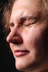 Obraz premium Sad woman crying on black background, closeup