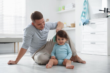 Obraz premium Father brushing his baby's hair on floor in bathroom