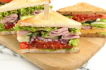 Tasty sandwiches with ham and vegetables on white table, closeup