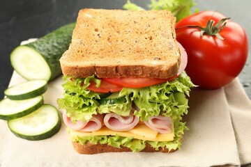 Tasty sandwich with ham, cheese and vegetables on table, closeup