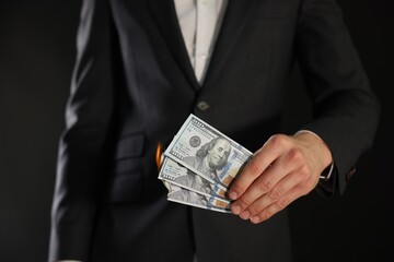 Man burning dollar banknotes on black background, closeup