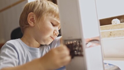 Concentrated little boy grating chocolate for dessert