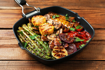 Delicious grilled vegetables, mushrooms and spices in pan on wooden table, closeup