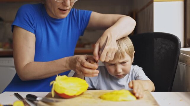 Mother teaching son how to cut fruit with knife