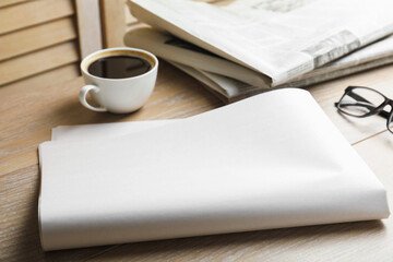 Newspapers, coffee and glasses on wooden table, closeup