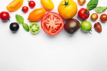 Ripe colorful tomatoes and basil on white background, flat lay. Space for text