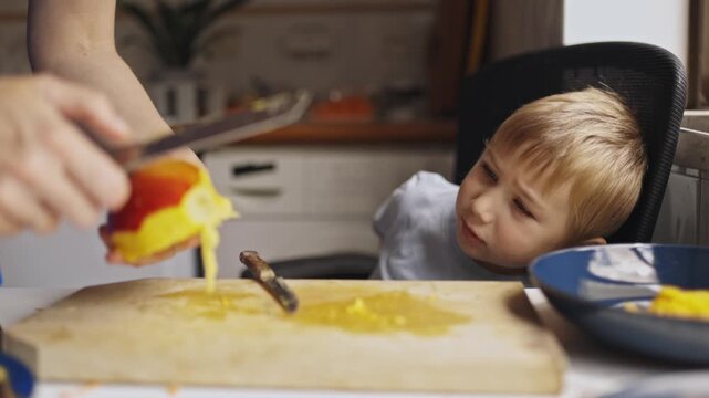 Mother peeling fresh mango for her little son
