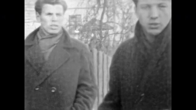 Youthful men stand annoyed, unhappy about camera presence, faces tense and angry, visible problem between locals and filmmaker, raw urban reaction. Old film. Archival retro 1960s. Vintage archive.