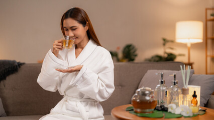 Asian woman enjoys relaxing herbal tea in white bathrobe at home spa environment self care for wellness calm peaceful moment