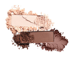 close-up photograph of two rectangular eyeshadow pans with crushed cosmetic powder scattered around them, featuring nude and deep brown shades isolated on black.