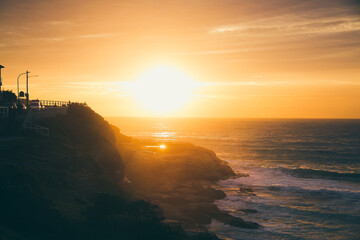 Obraz premium Golden sunrise over Bronte Beach cliffs and ocean in Sydney, Australia