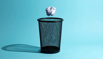 Crumpled paper being tossed into a trash can on a bright teal background, waste