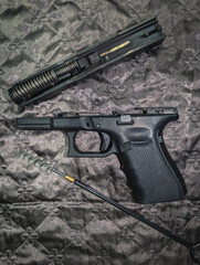 A modern semi-automatic pistol is field-stripped for routine cleaning and maintenance, with its slide, frame, and bore brush laid out