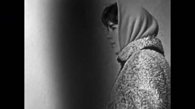Beautiful young woman in profile, portrait in headscarf indoors. Winter clothing retro 1960s fashion. Attractive girl face is worried, concerned emotional. Old film. Archival retro. Vintage archive