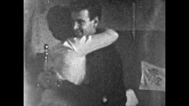 Young couple glide in room, man and woman embrace during slow dance, joyful smiles and romantic connection, gentle steps and warm togetherness. Old film. Archival retro 1960s. Vintage archive.