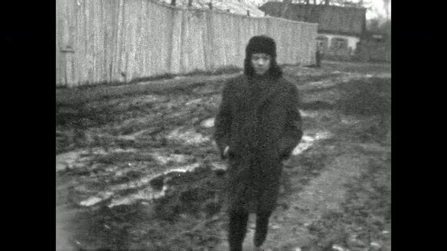 Young funny man walking down old street, raising arms in cheerful greeting, smiling with carefree energy. Playful moment full of joy and freedom. Old film. Archival retro 1960s. Vintage archive.