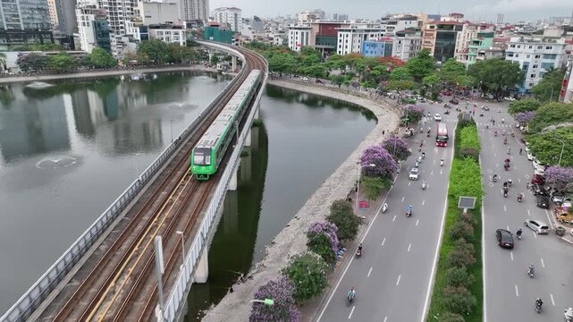 Cat Linh&ndash;Ha Dong metro train running along Hoang Cau lake, vibrant urban morning scene.