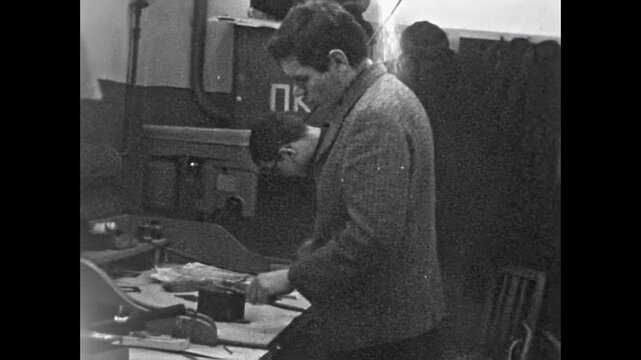 Focused factory worker working at production facility. Worker making parts by hand in industrial workbench. Craftsmanship in vintage manufacturing. Old technology film. Archival retro archive