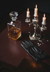 stylish arrangement featuring a crystal decanter, lit candles on a polished surface, and a black glove, elegant atmosphere.
