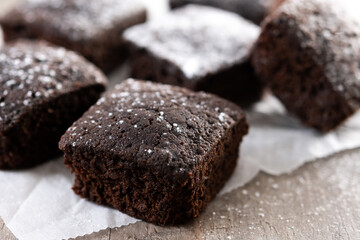 Homemade chocolate brownies with sugar powder on wooden table. Close up