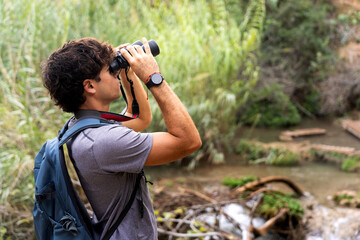 Hiker man observing nature through binoculars