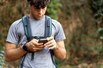 Young man navigating during autumn trekking with smartphone